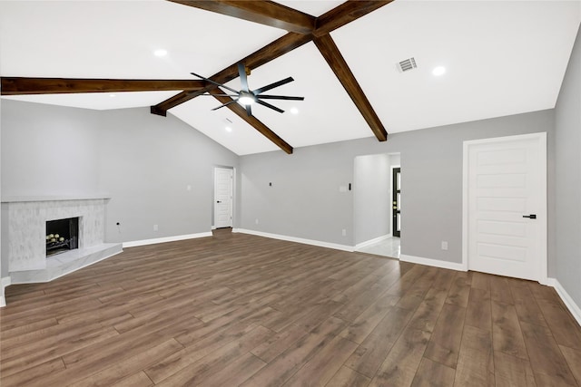 unfurnished living room with wood-type flooring, a premium fireplace, ceiling fan, high vaulted ceiling, and beam ceiling