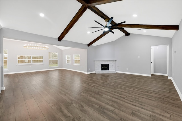 unfurnished living room with ceiling fan with notable chandelier, vaulted ceiling with beams, dark hardwood / wood-style floors, and a fireplace