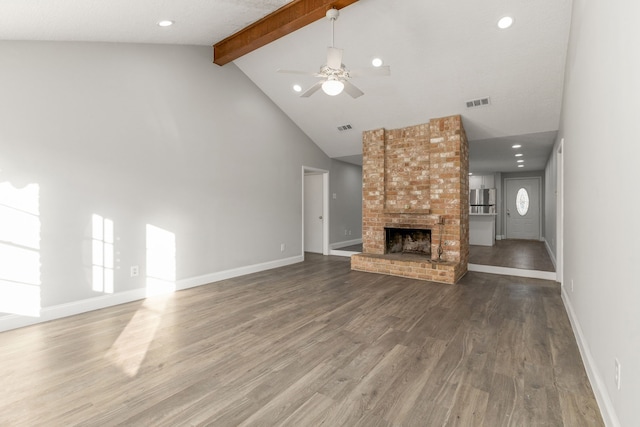 unfurnished living room featuring wood-type flooring, ceiling fan, high vaulted ceiling, beamed ceiling, and a brick fireplace