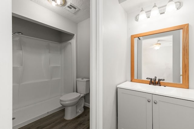 bathroom featuring a textured ceiling, vanity, toilet, and walk in shower