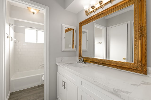 full bathroom featuring toilet, vanity, tiled shower / bath combo, and wood-type flooring