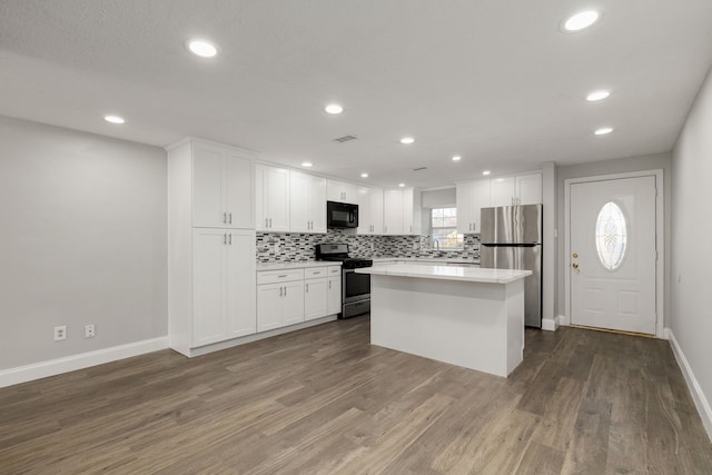 kitchen featuring appliances with stainless steel finishes, white cabinetry, a center island, and hardwood / wood-style floors