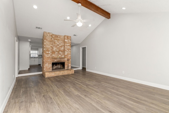 unfurnished living room with wood-type flooring, beamed ceiling, ceiling fan, a fireplace, and high vaulted ceiling