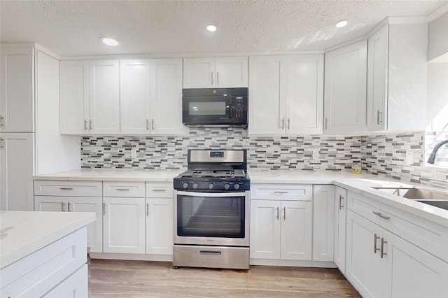 kitchen with white cabinetry, sink, stainless steel range with gas stovetop, and light wood-type flooring