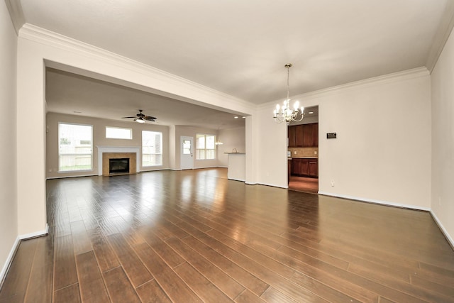 unfurnished living room featuring ceiling fan with notable chandelier, dark wood-type flooring, and crown molding