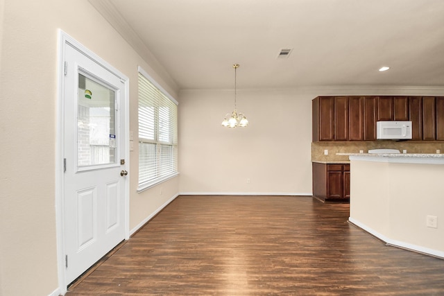 kitchen with dark hardwood / wood-style flooring, ornamental molding, backsplash, a chandelier, and pendant lighting