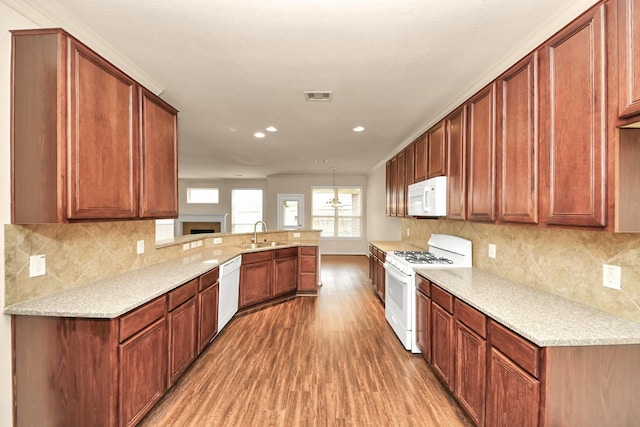 kitchen with kitchen peninsula, sink, white appliances, dark wood-type flooring, and pendant lighting