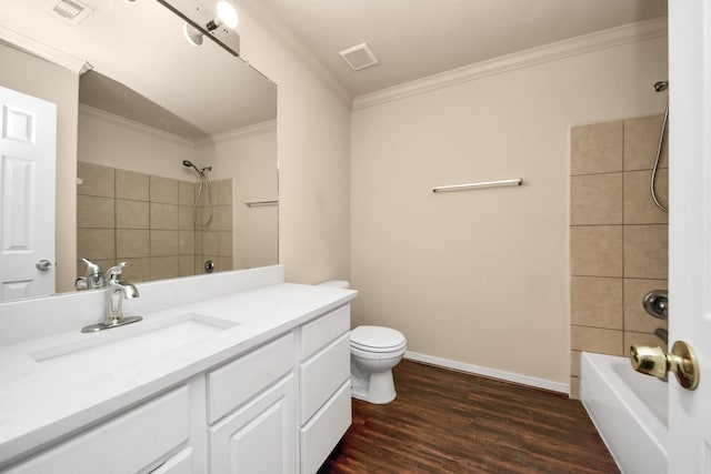 full bathroom featuring vanity, tiled shower / bath, toilet, hardwood / wood-style flooring, and ornamental molding