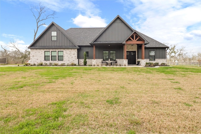 view of front of house featuring brick siding, a shingled roof, board and batten siding, a front yard, and fence