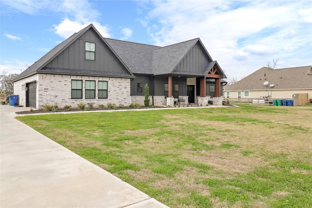 view of front facade with board and batten siding, a front yard, brick siding, and a shingled roof