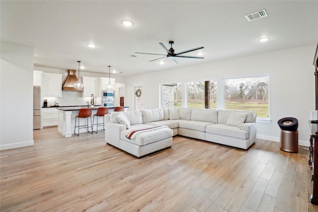 living room with baseboards, light wood-type flooring, visible vents, and recessed lighting