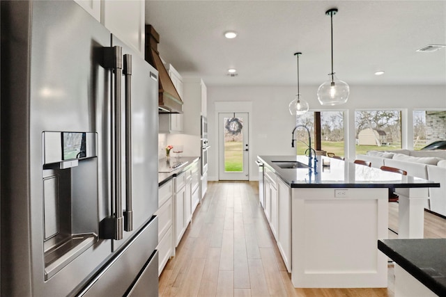 kitchen with appliances with stainless steel finishes, dark countertops, white cabinets, and a sink