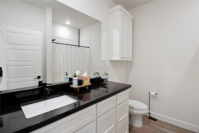 bathroom with toilet, a shower with shower curtain, wood finished floors, vanity, and baseboards