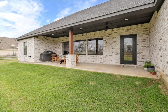 rear view of house featuring brick siding, a shingled roof, a lawn, a patio area, and ceiling fan