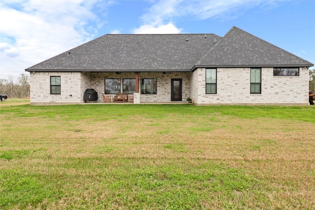 back of house featuring a yard, a shingled roof, a patio, and brick siding