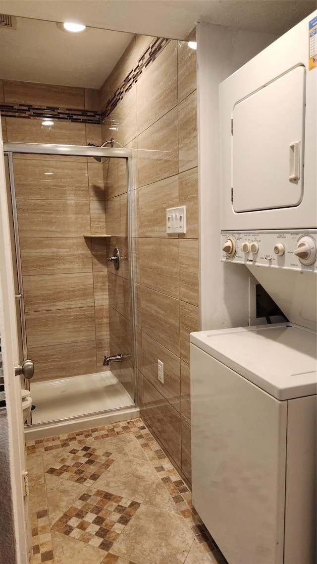 bathroom featuring stacked washer / dryer and a shower with shower door