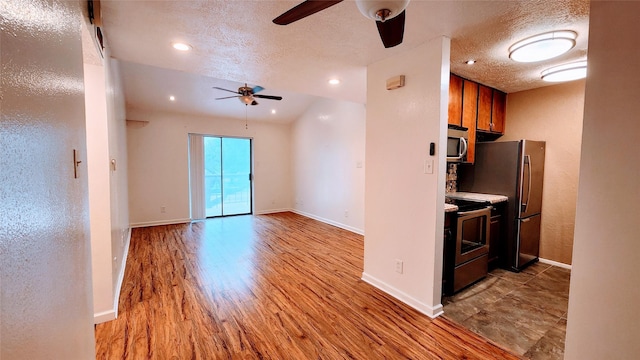 kitchen featuring a textured ceiling, appliances with stainless steel finishes, ceiling fan, and light hardwood / wood-style flooring