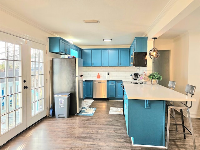 kitchen with blue cabinets, a kitchen breakfast bar, light countertops, appliances with stainless steel finishes, and hanging light fixtures