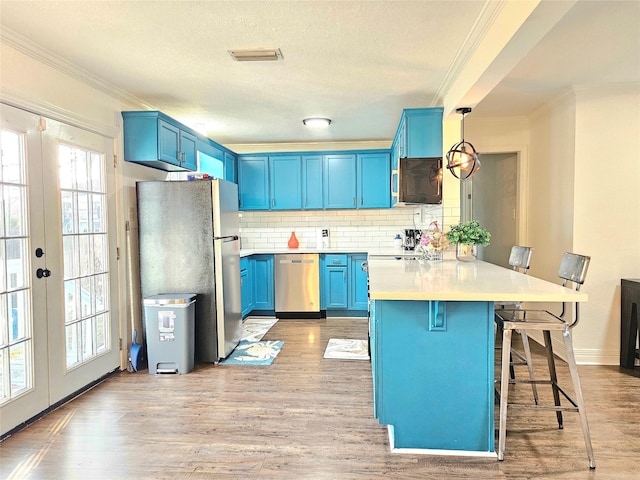 kitchen with french doors, light countertops, hanging light fixtures, appliances with stainless steel finishes, and blue cabinets