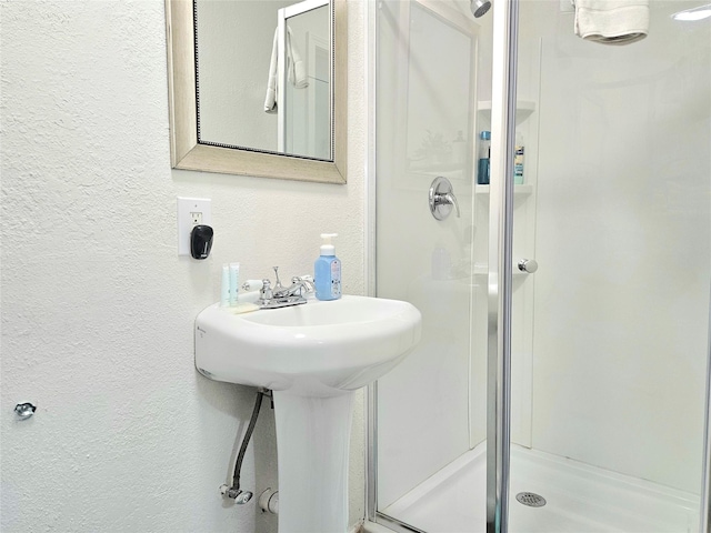 bathroom with a textured wall and a shower stall