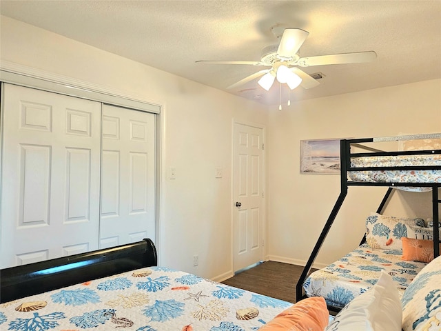 bedroom with a textured ceiling, dark wood-style flooring, a ceiling fan, baseboards, and a closet