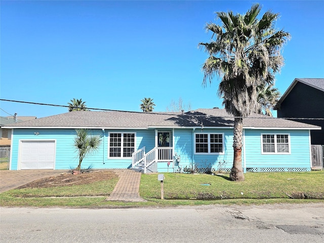 ranch-style home featuring a front lawn, decorative driveway, and an attached garage