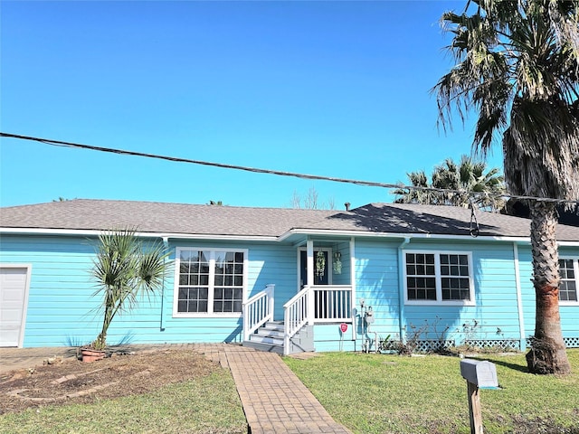 ranch-style home with a garage, roof with shingles, and a front yard