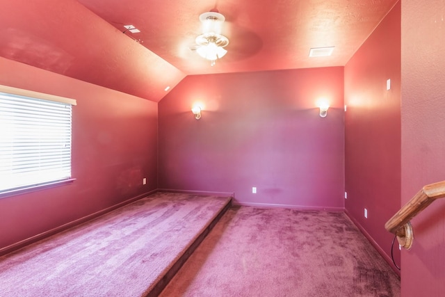 carpeted home theater room with ceiling fan and vaulted ceiling