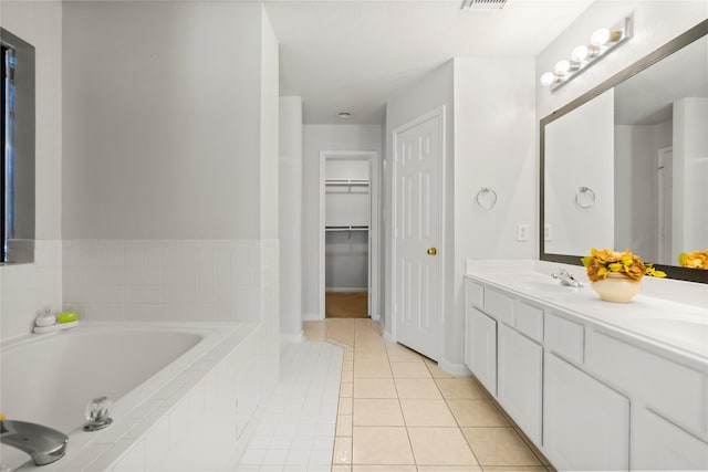 bathroom featuring tiled bath, tile patterned flooring, and vanity