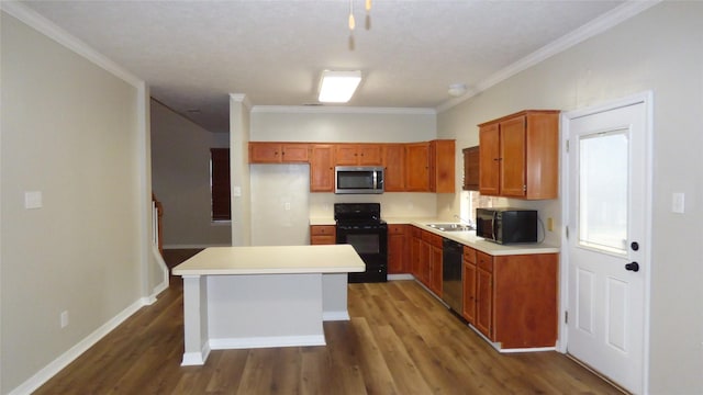 kitchen with brown cabinetry, a center island, light countertops, black appliances, and a sink