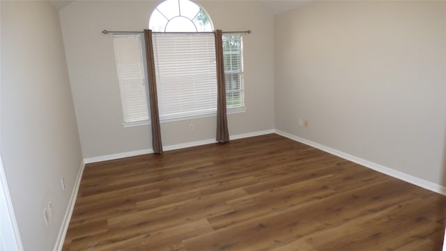 spare room featuring dark wood-type flooring and vaulted ceiling