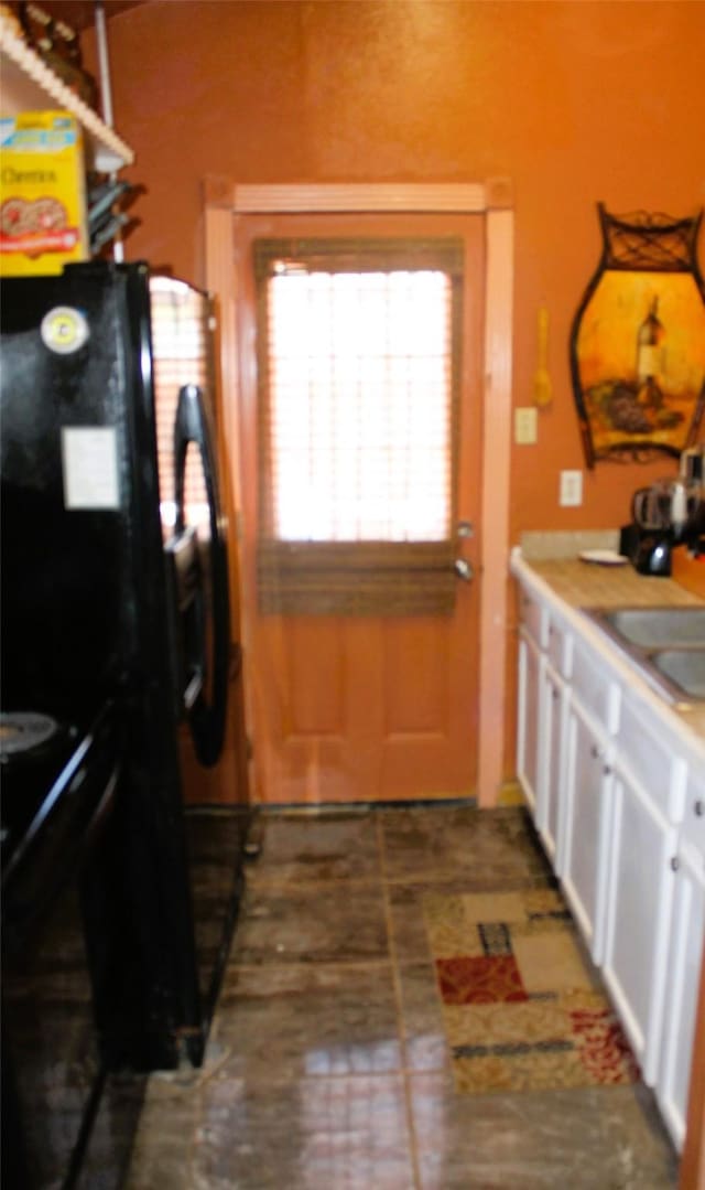 kitchen with white cabinets, sink, black fridge with ice dispenser, and electric range oven