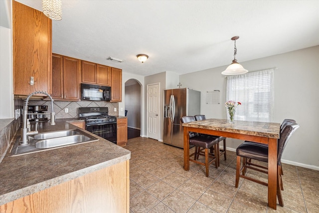 kitchen with sink, light tile patterned flooring, black appliances, hanging light fixtures, and decorative backsplash