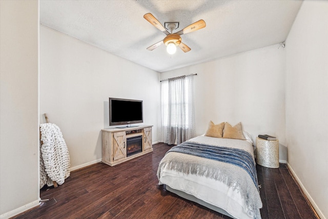 bedroom featuring ceiling fan, dark hardwood / wood-style flooring, and a textured ceiling