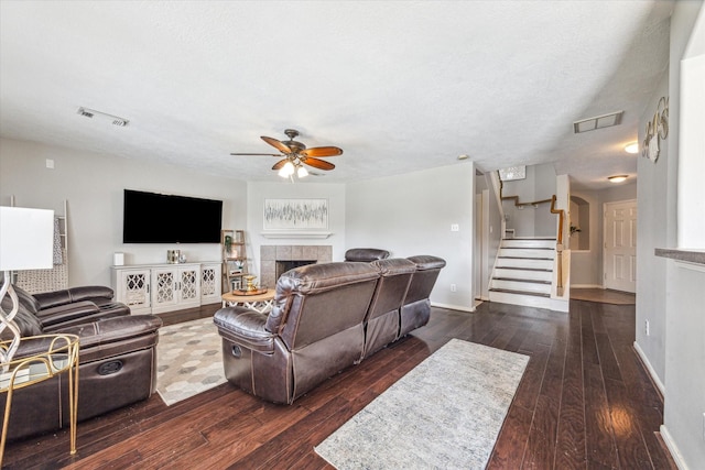 living room with a fireplace, ceiling fan, a textured ceiling, and dark hardwood / wood-style flooring