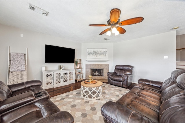 living room with a fireplace, hardwood / wood-style flooring, a textured ceiling, and ceiling fan