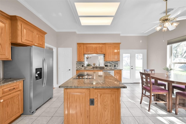 kitchen with appliances with stainless steel finishes, light tile patterned flooring, a kitchen island, and backsplash