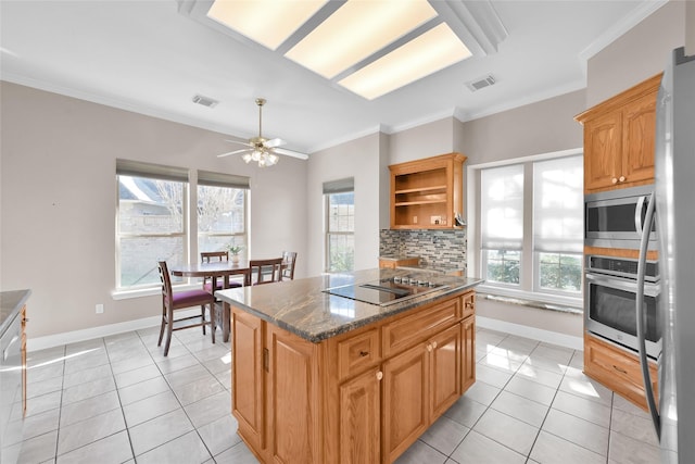 kitchen featuring appliances with stainless steel finishes, backsplash, a center island, dark stone counters, and ornamental molding