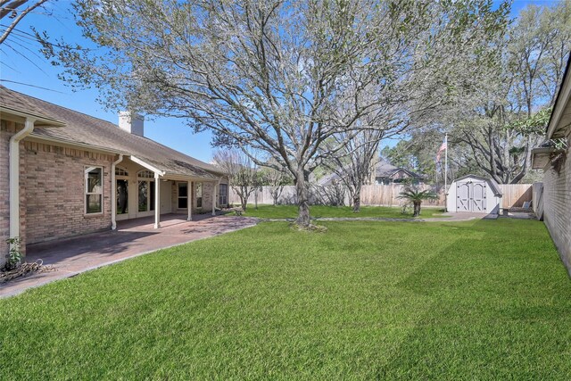 view of yard featuring a storage unit, an outdoor structure, and a patio area