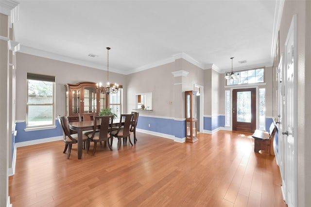 dining area featuring ornamental molding, light hardwood / wood-style flooring, and an inviting chandelier