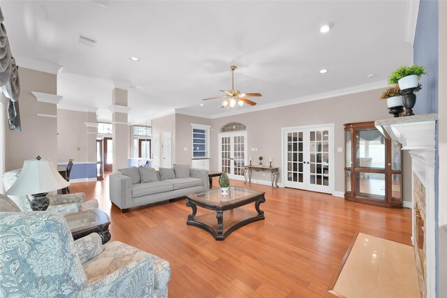 living room featuring french doors, wood finished floors, a ceiling fan, crown molding, and a fireplace with flush hearth