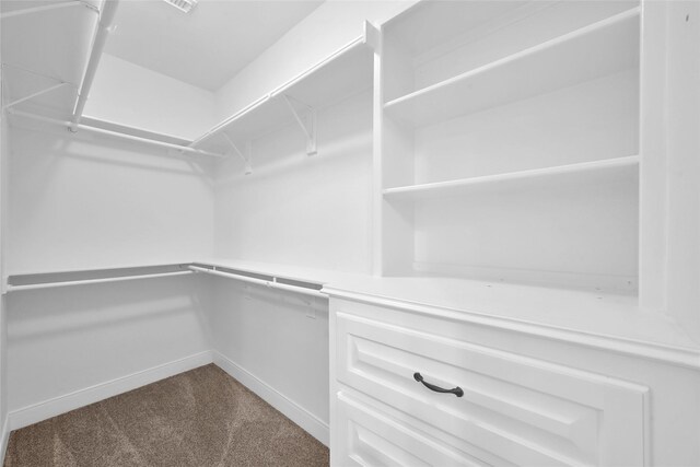 walk in closet with dark colored carpet
