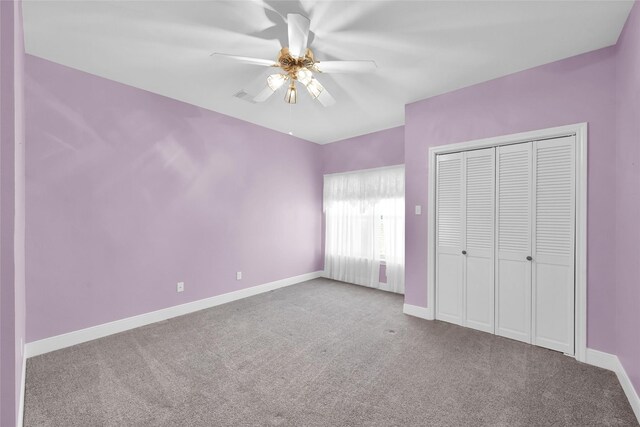 unfurnished bedroom with carpet, baseboards, a closet, and a ceiling fan