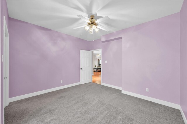 empty room with ceiling fan, carpet floors, and baseboards