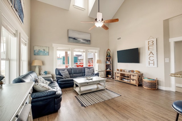 living area featuring baseboards, high vaulted ceiling, wood finished floors, and a ceiling fan