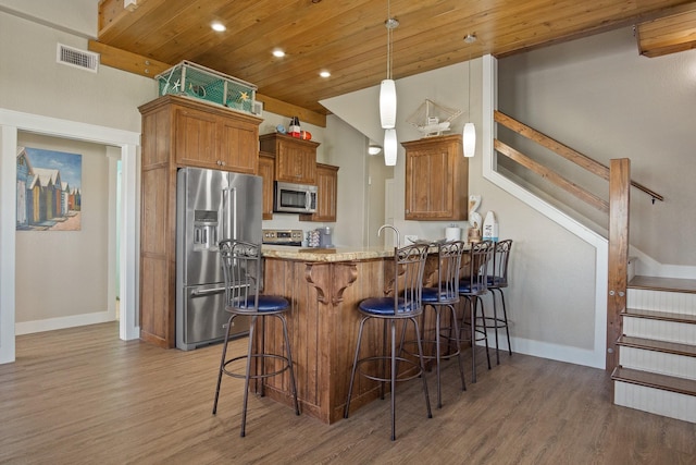 kitchen with stainless steel appliances, brown cabinetry, visible vents, and a peninsula