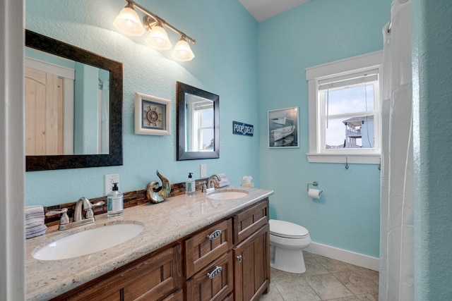 bathroom featuring baseboards, a sink, toilet, and double vanity