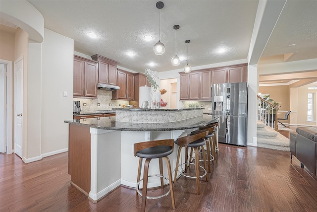 kitchen with a center island, dark hardwood / wood-style flooring, hanging light fixtures, and stainless steel fridge