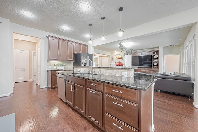 kitchen with sink, pendant lighting, dark hardwood / wood-style flooring, stainless steel dishwasher, and a kitchen island with sink