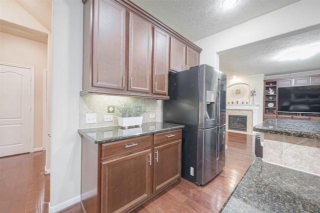 kitchen featuring light hardwood / wood-style flooring, tasteful backsplash, a textured ceiling, and stainless steel refrigerator with ice dispenser